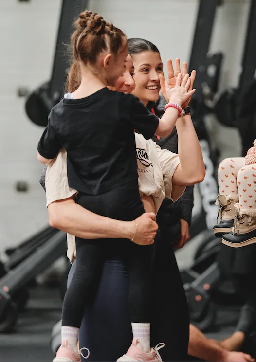 Coach Sandrine qui fait un high-five à une jeune athlète après une séance.