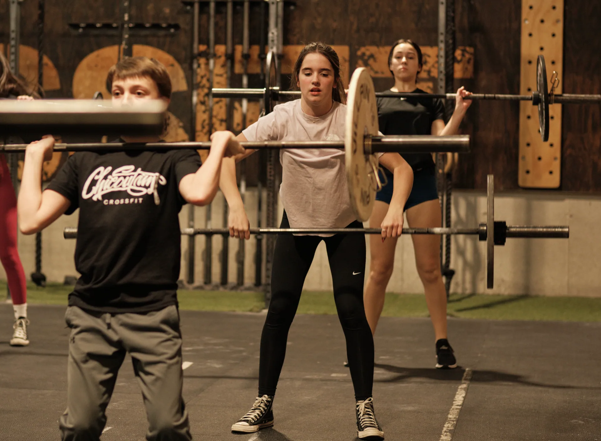 Trois jeunes athlètes Sport-études en position front squat avec barre olympique.